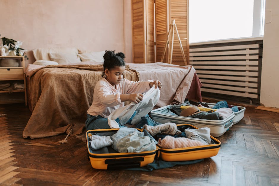 Young girl folding clothes and packing a suitcase in a warm, cozy bedroom.