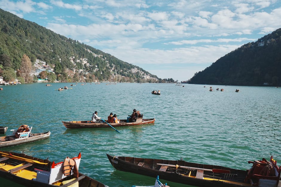 Idyllic view of people boating on Nainital Lake with lush hills and clear skies.