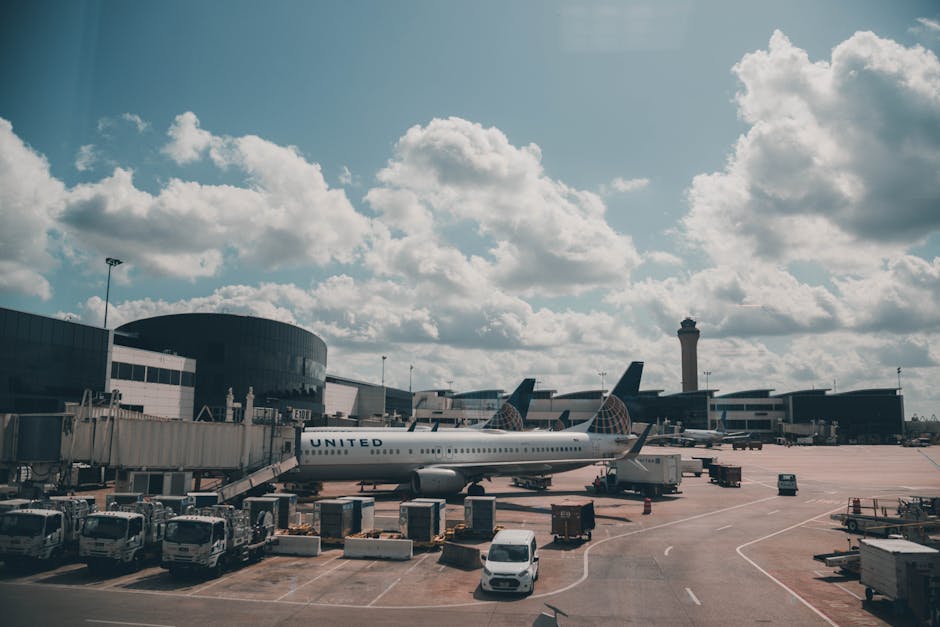 A United airplane parked on the airport apron under a scenic cloudy sky.