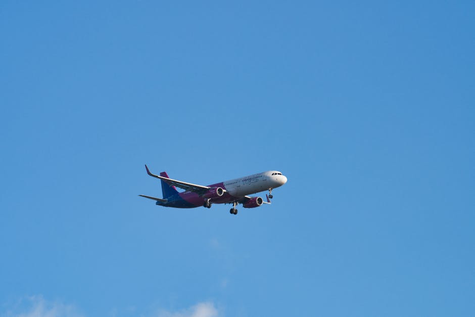 A commercial airliner flying against a clear blue sky, captured during daytime.