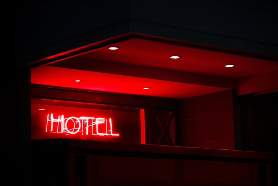 A vibrant red neon sign reading 'Hotel' glows in the night, casting a modern ambiance.