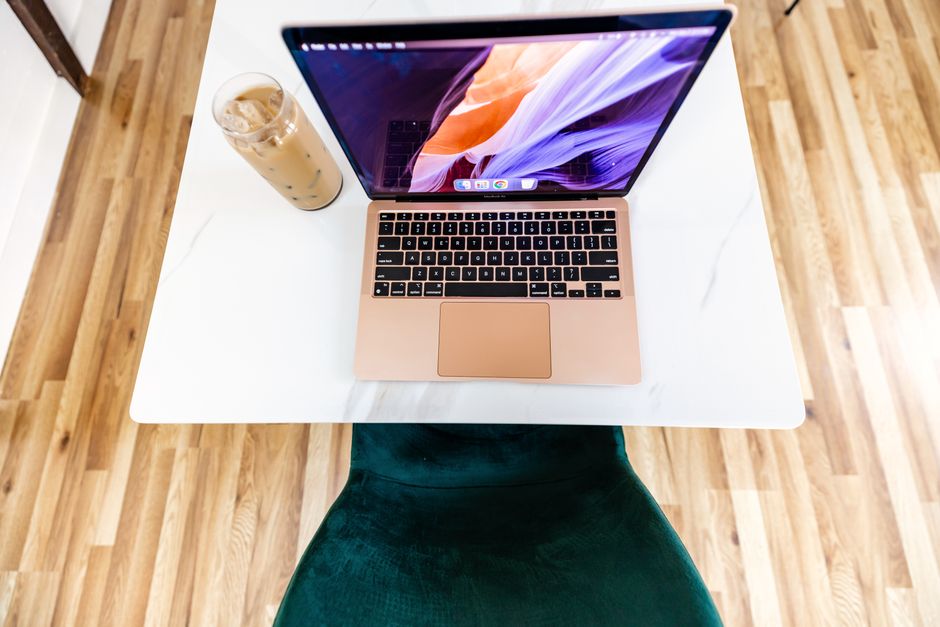 Top view of a stylish workspace featuring a laptop and iced coffee on a marble desk.
