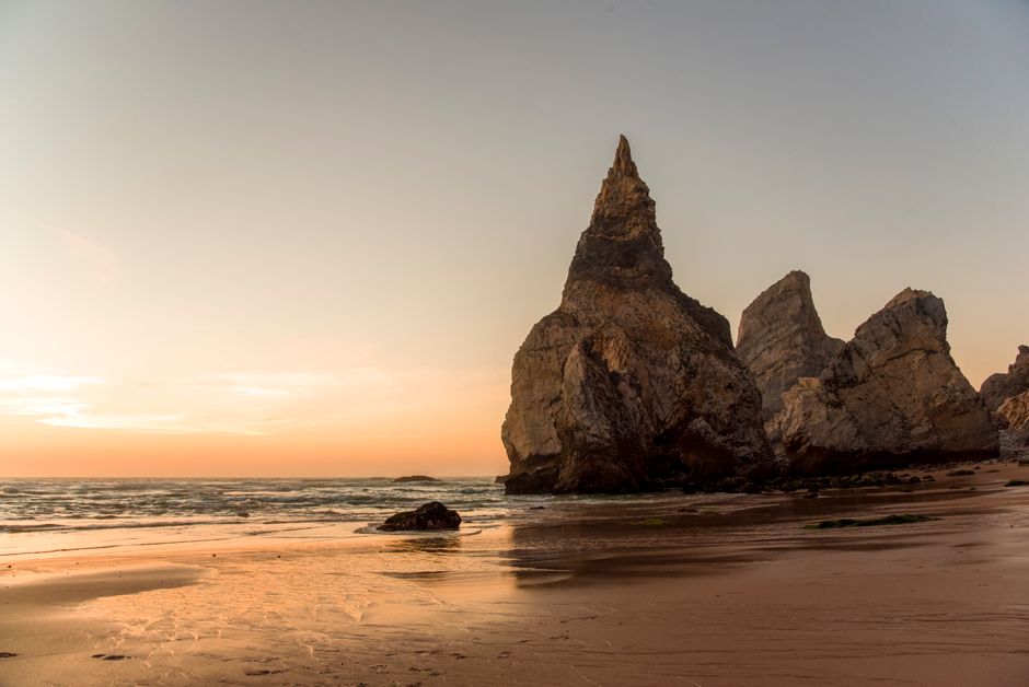 Sunset view of Praia da Ursa's unique rock formations along the Portuguese coast.