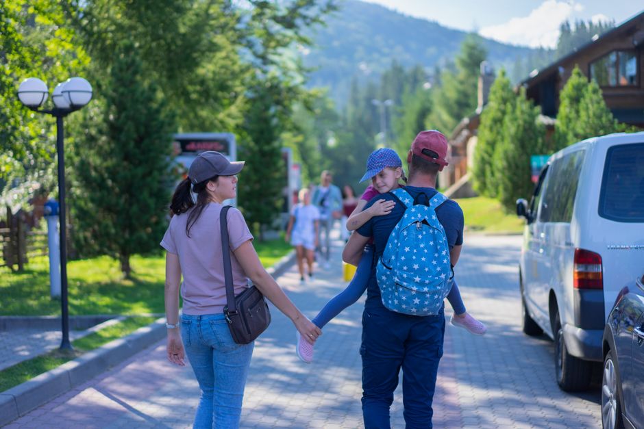 Parents walking with their daughter in a picturesque mountain village, enjoying a sunny da