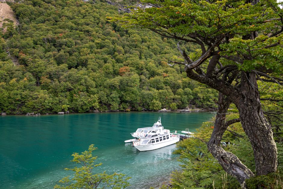 Serene lake view in Santa Cruz, Argentina, with a boat docked amidst lush greenery.