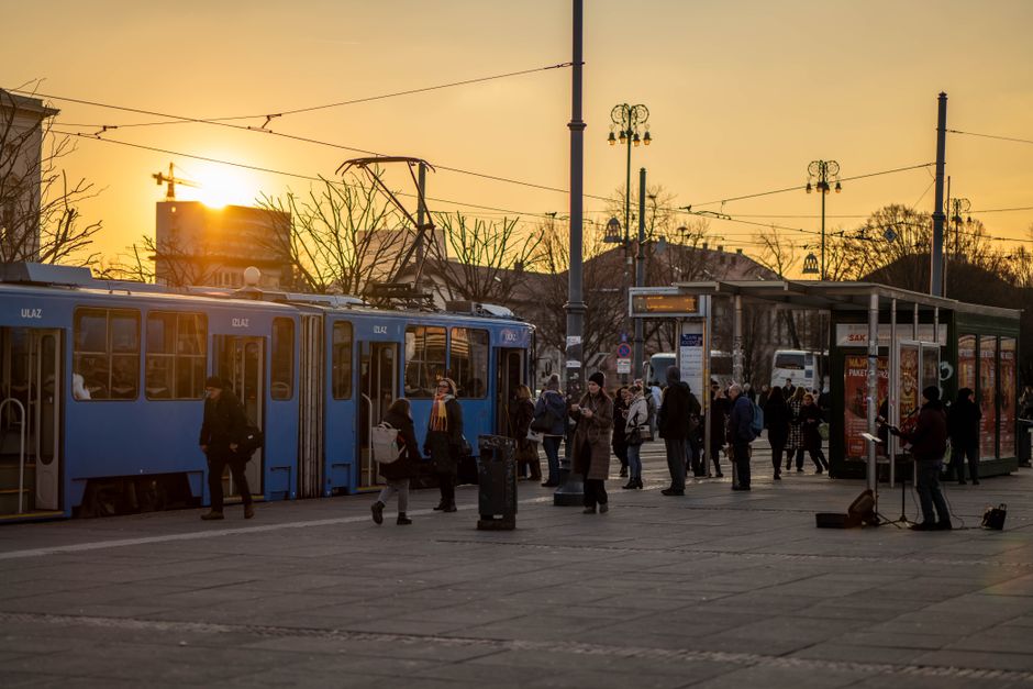 People boarding trams during sunset in Zagreb, creating a vibrant urban scene with warm to