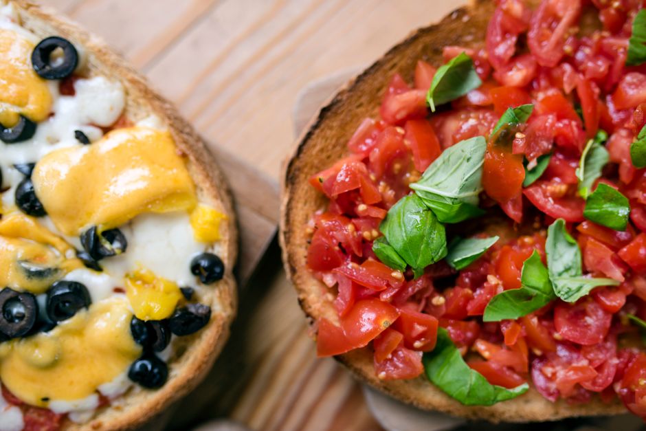 Overhead view of delicious toasts with black olive rings and melted cheese on wooden table