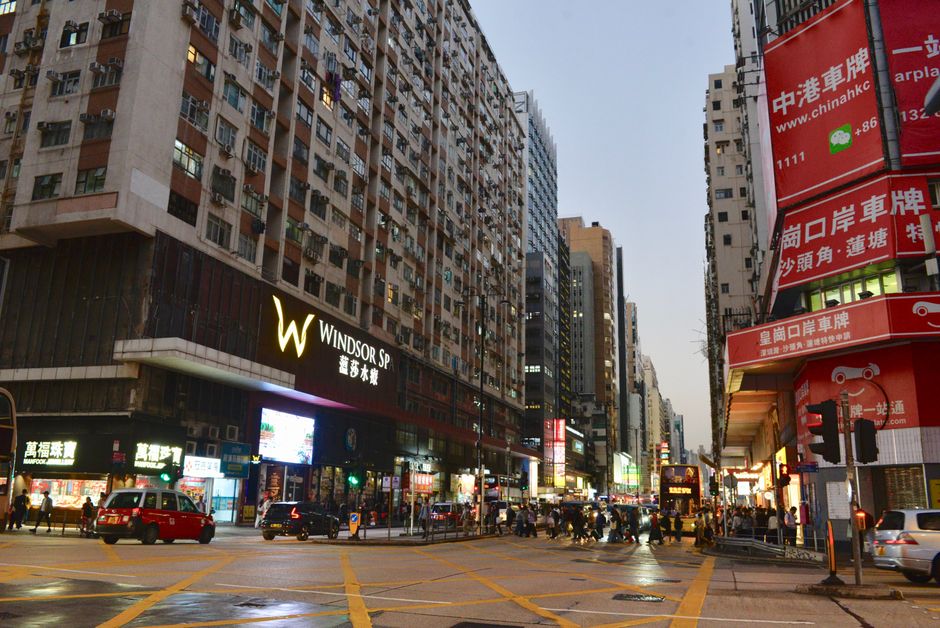 Vibrant Hong Kong street scene at dusk, showcasing tall buildings and bustling traffic.