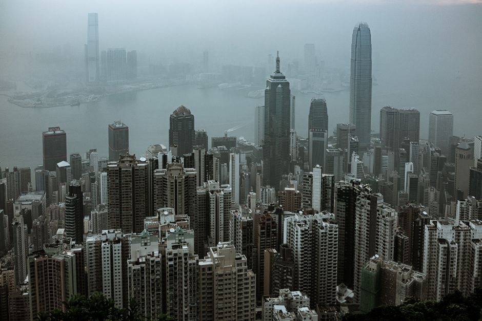 Aerial view of Hong Kong's iconic skyscrapers shrouded in fog over Victoria Harbour.