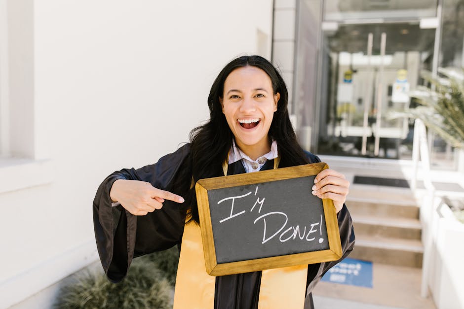 Happy woman in graduation gown holding 'I'm done!' sign, celebrating success.